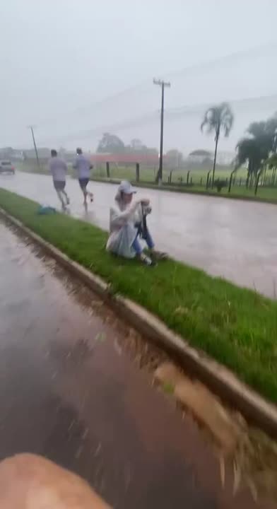Fotógrafo agachado com câmera e proteção durante uma cobertura na chuva